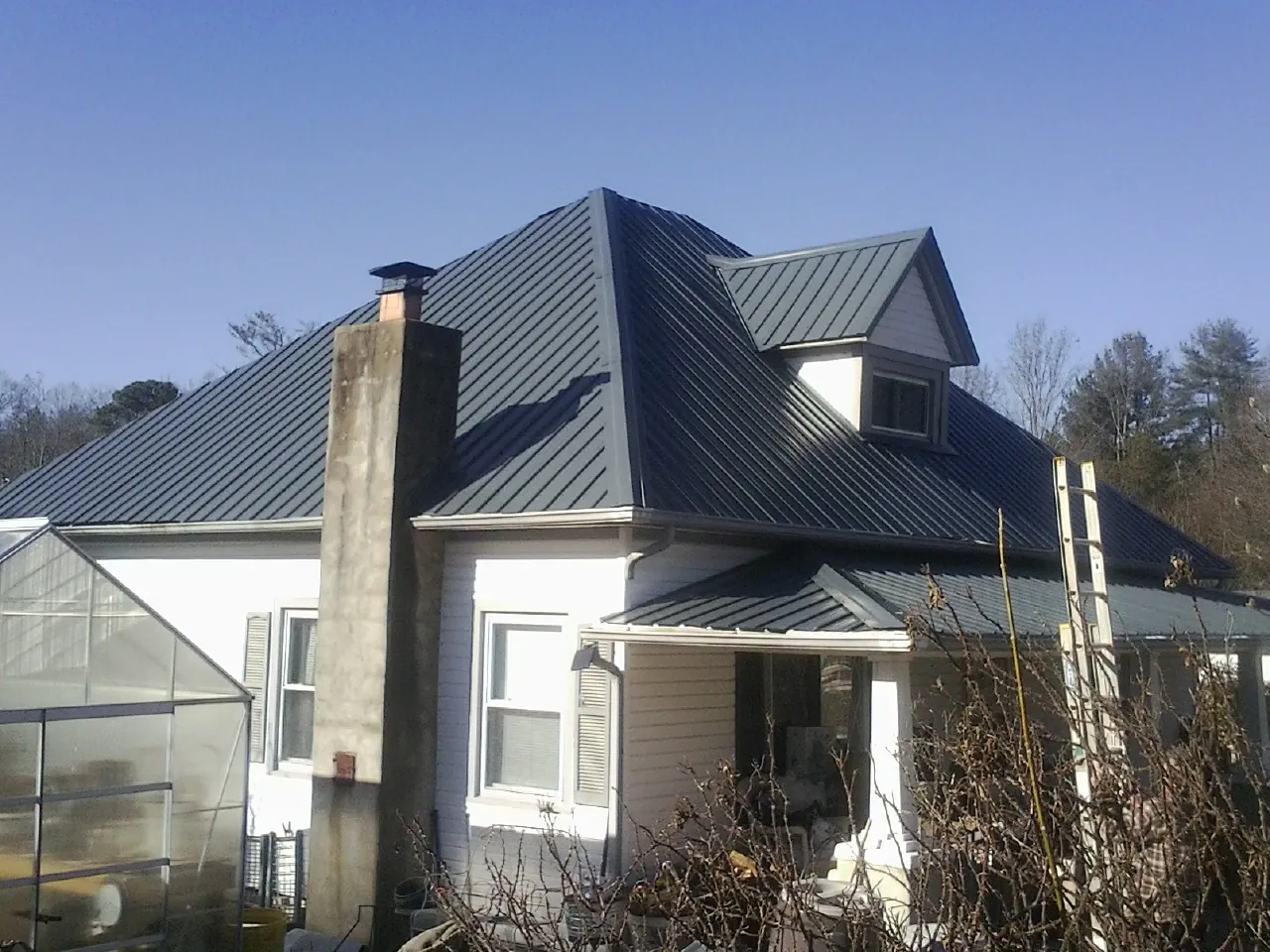 Dark blue standing seam metal roof on a white farmhouse with dormer — Slate & Tile Roof Repair by Roofing Brothers in Rockbridge Baths