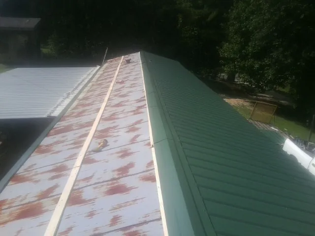 Old rusted panels beside newly installed green metal roofing — Wind Damage Roof Repair by Roofing Brothers in Rockbridge Baths
