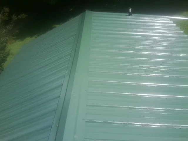 New green metal panels meeting at the ridge of a roof — Flat Roof Repair work by our crew in Rockbridge Baths