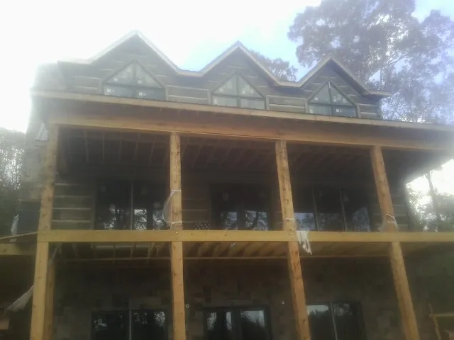 Dormers and porch framing on a large log home under construction — Roof Coating work by our crew in Rockbridge Baths