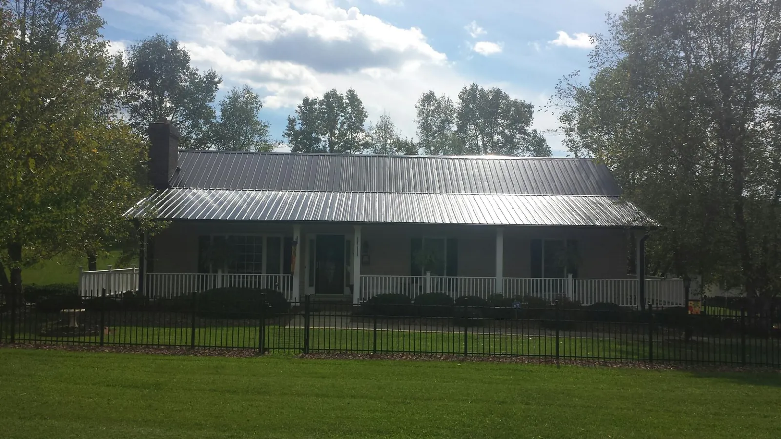 Gray metal roof on a brick ranch with a full width front porch — Gutter Guard Installation work by our crew in Rockbridge Baths
