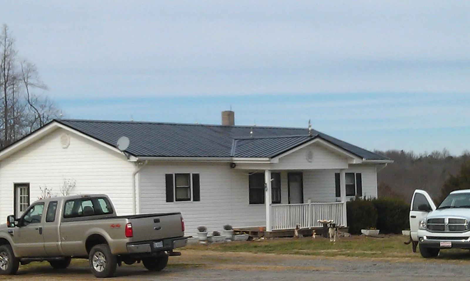 Finished dark metal roof on a white ranch home with work trucks parked in Rockbridge Baths