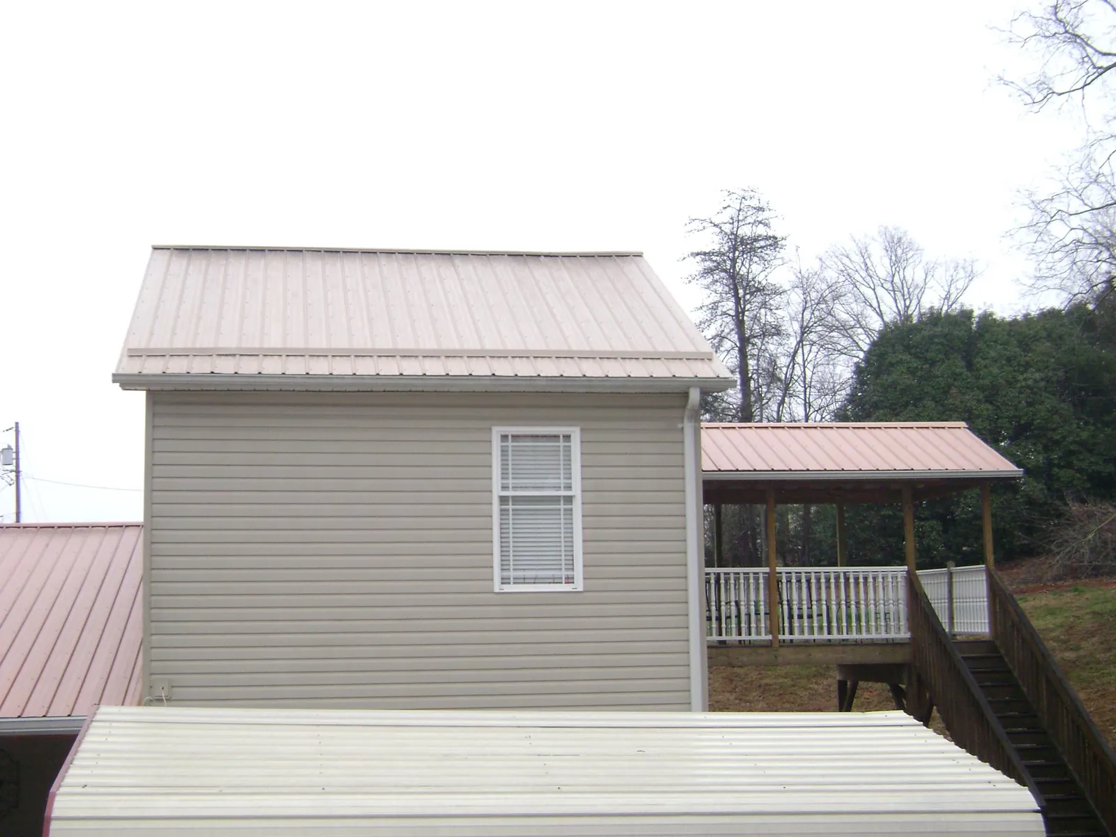 Tan metal roofs on a two story addition and attached porch, from a Roof Replacement job in Rockbridge Baths